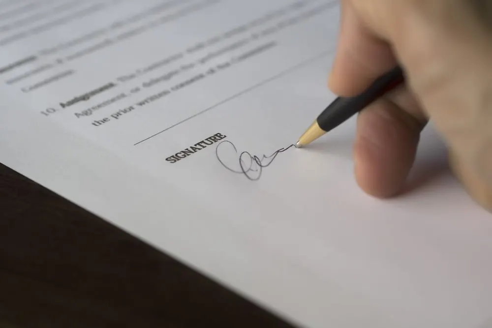 A hand signing a printed document
