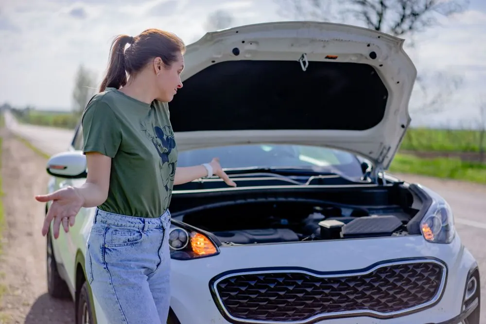 A driver standing beside her car with the bonnet raised