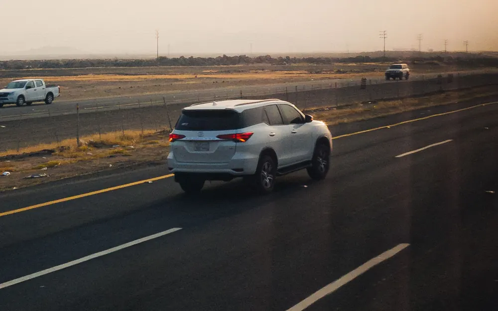 A car driving away along an open highway at sunset