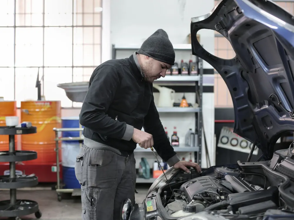 A technician working over an open engine bay in a workshop