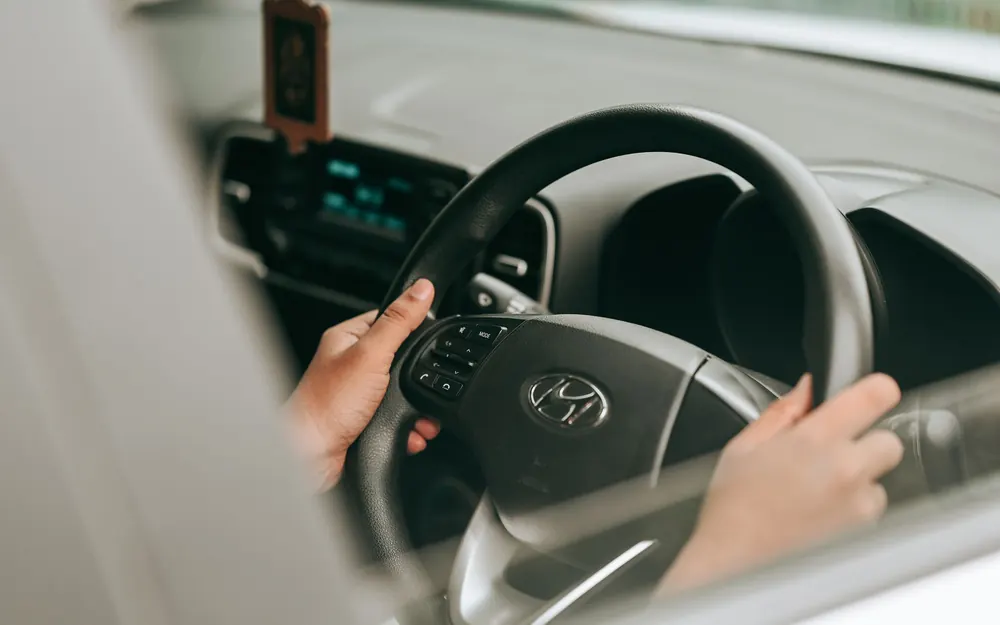 Hands resting on a car steering wheel