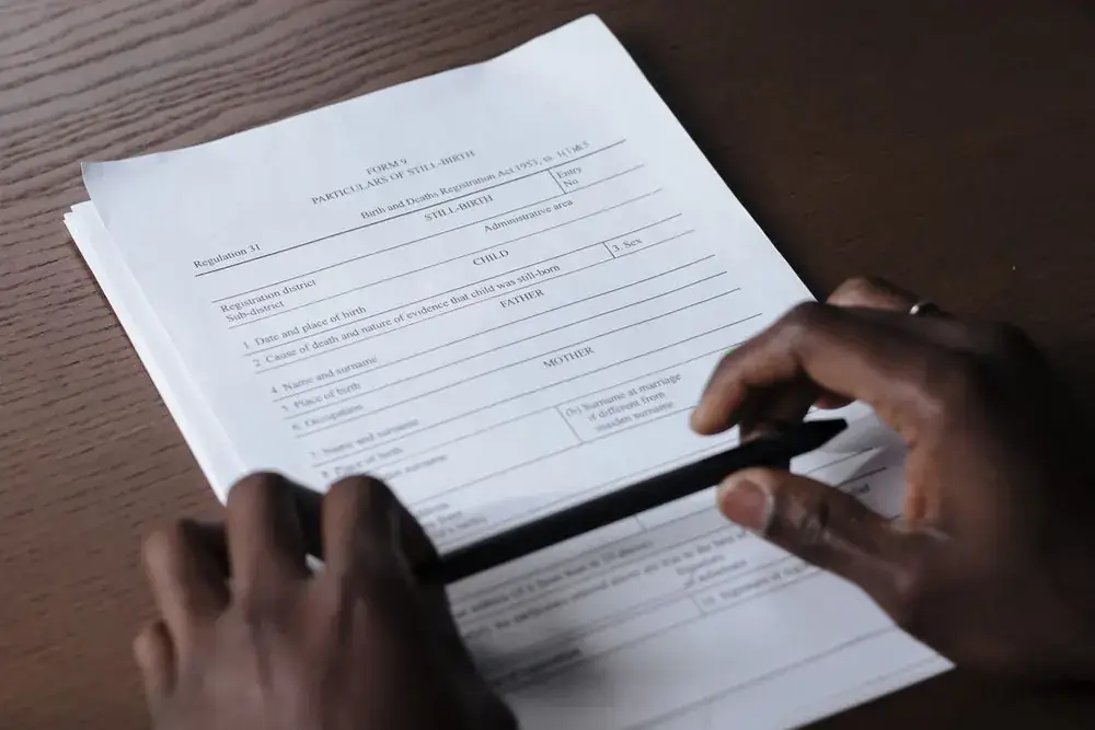 A hand working through a printed application form